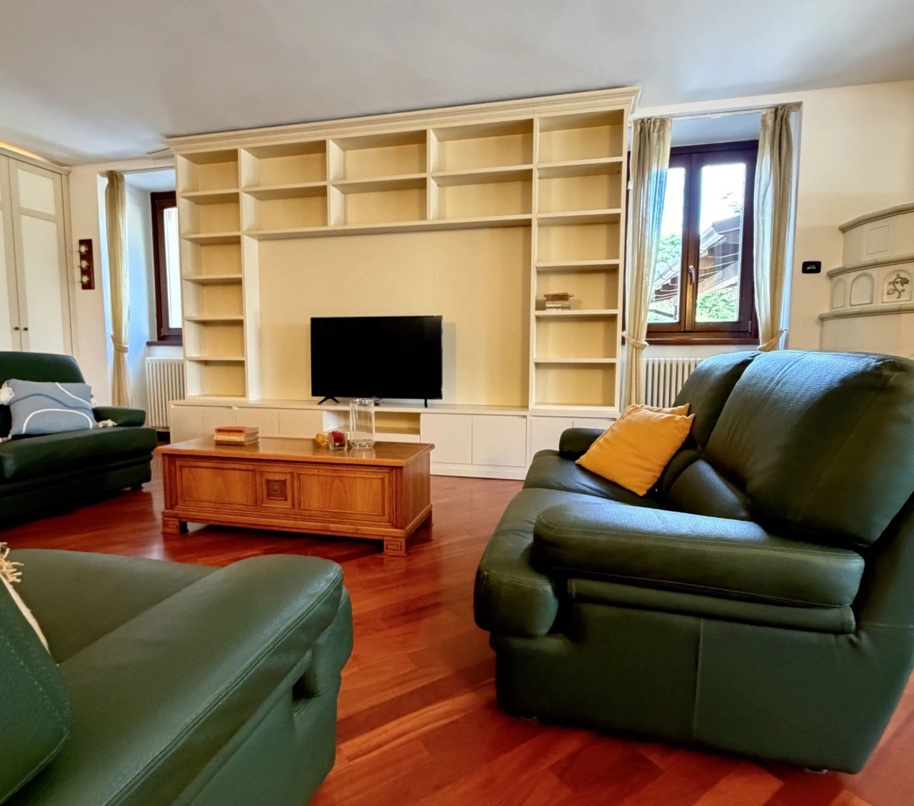Soggiorno con divani verdi e mobile TV nel case history Bridge Rent a Gallarate