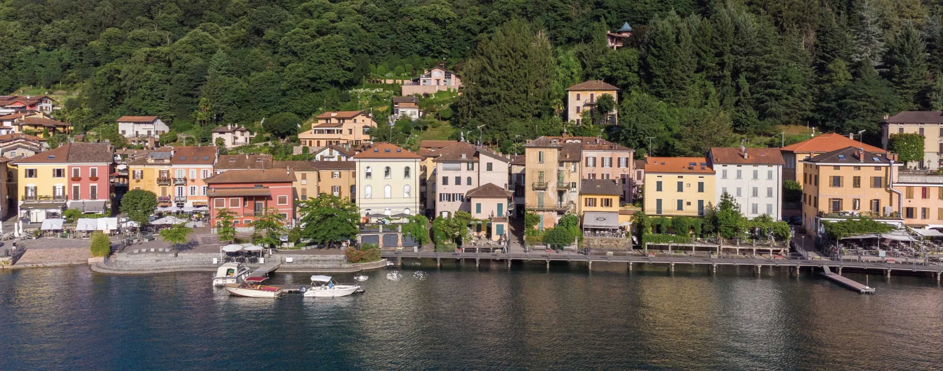 Borgo sul lungolago con case colorate e barche per Lakes Region Real Estate