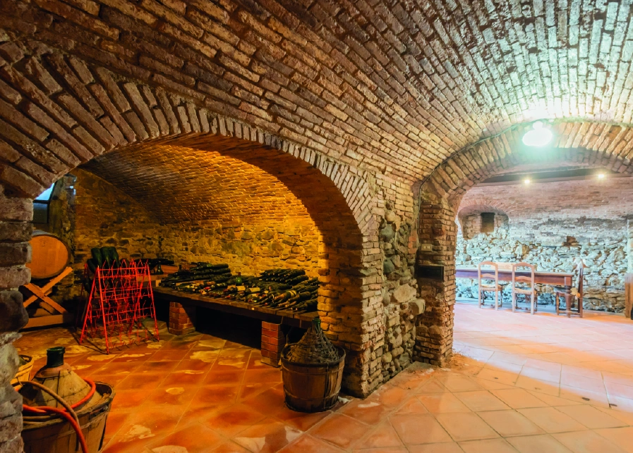 Cantina rustica con volta in mattoni e bottiglie di vino