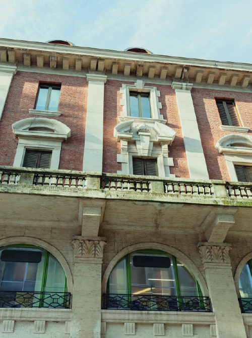 Facciata di palazzo storico in mattoni con archi e balconata